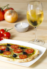 pesto pizza with tomatoes and black olives