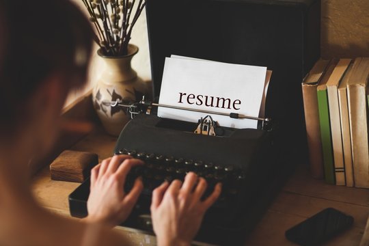 Resume against young woman using typewriter