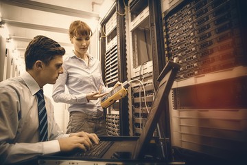 Team of technicians using digital cable analyser on servers