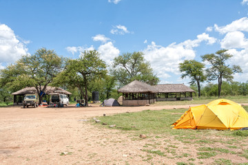 Safari campsite (camp-lodge) in savanna against blue sky background. Serengeti National Park, Great Rift Valley, Tanzania, Africa. 
