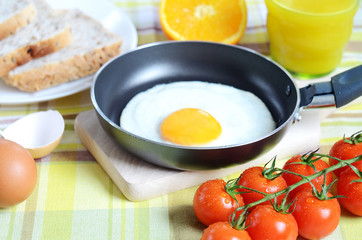 Fried egg, toast bread, fresh juice, tomatoes and oranges