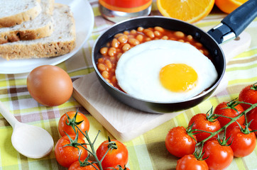 Fried egg with beans, toast bread, fresh juice, tomatoes and oranges
