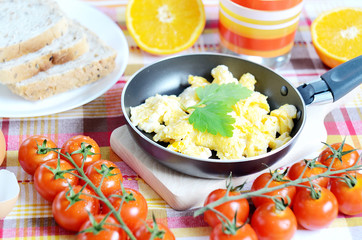 Scrambled eggs, toast bread, fresh juice, tomatoes and oranges