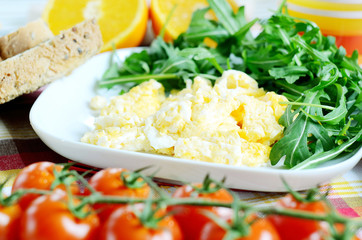 Scrambled eggs, toast bread, fresh juice, tomatoes and oranges