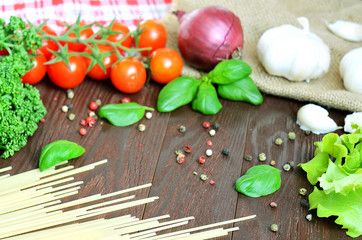 Tomatoes, spaghetti, onion and garlic on wooden table