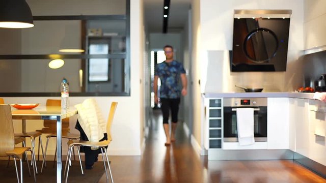 Man in sporty clothing walking in the flat, steadycam shot
