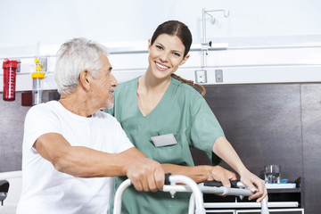 Nurse Assisting Senior Man To Use Walker At Rehab Center