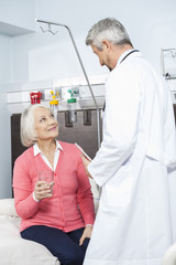 Senior Patient Holding Water Glass While Looking At Doctor