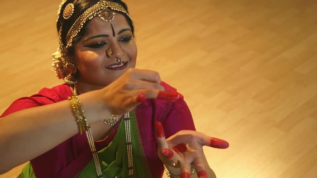The traditional jewelry and painted fingers accent the mudra or hand gestures of a lovely traditional Indian dancer.