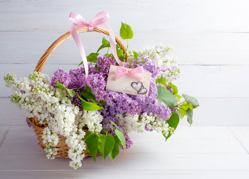 Lilac bouquet in basket with paper greeting card with hearts and