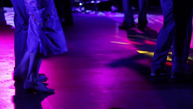 Legs of couple learning to dance tango and honing skills in a dancing class hall. First steps. Close up