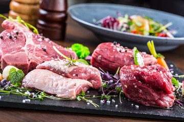 Steak.Beef steak.Meat.Portioned meat.Raw fresh meat.Sirloin steak.T-Bone steak. Flank steak. Duck breast. Vegetable decoration. Portioned meat prepared for processing in a restaurant or hotel kitchen.