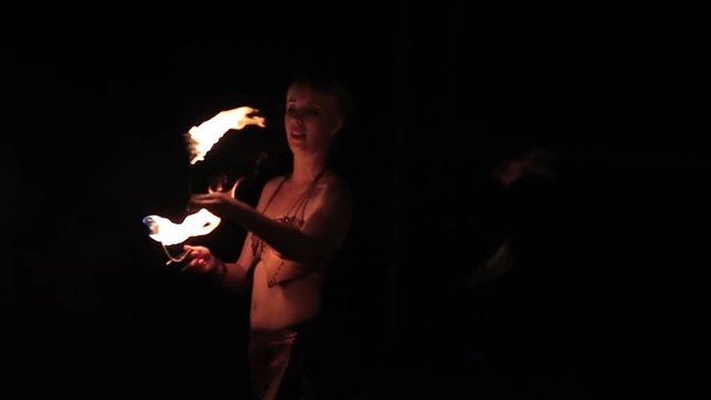 Fire show performance. Female fire performers dance with burning fire torches on a black background. Close-up. Slow motion