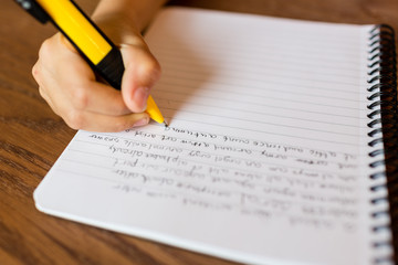 Child writing by hand on notepad