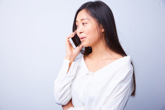 Chinese Woman In White Talking On A Cell Phone