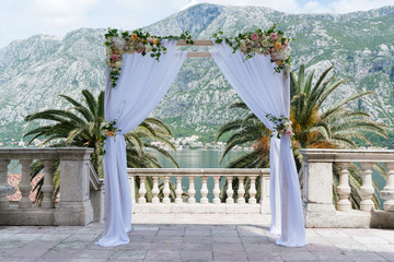 arch for the wedding ceremony, decorated with cloth flowers and greenery