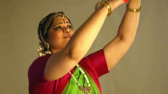 The painted fingers and adornment of bangles  and bracelets accent the hand gestures of a traditional Indian dancer.