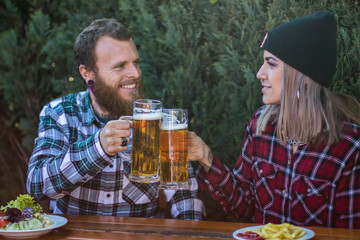 Junges Paar mit Augenkontakt prostet sich zu mit Biergläsern