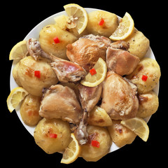 Plateful of Oven Baked, Rosemary sprinkled, Chicken Legs and Potato, Garnished with Lemon Slices, and small Tomato square shaped cutoffs, Isolated on Black Background.