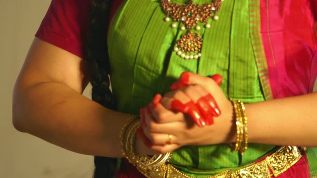 The painted fingers and adornment of bangles  and bracelets accent the hand gestures of a traditional Indian dancer.