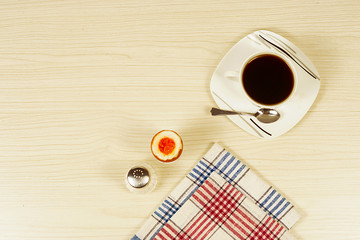 Coffee in a cup and a soft-boiled egg.