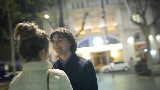 Couple holding hands while standing in the city at night, steadycam shot
