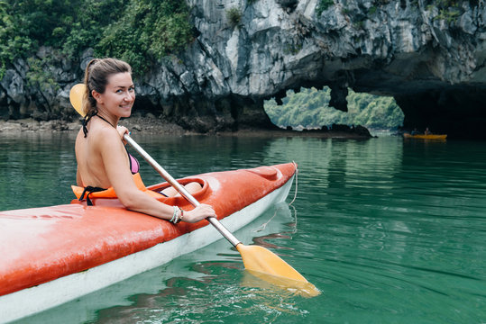 Woman rowing kayak and smile in Halong Bay.