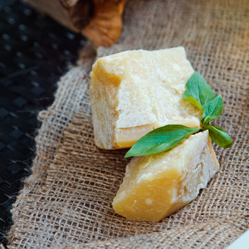 Beautiful fresh Parmesan cheese with a Basil leaf on a background of burlap