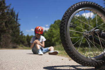 Boy is lying hurt after a bicycle accident. Kids safety concept