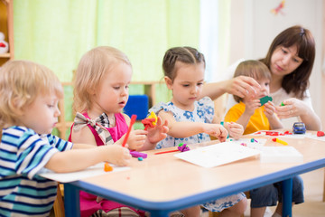 Obraz na płótnie Canvas kids learning arts and crafts in kindergarten with teacher