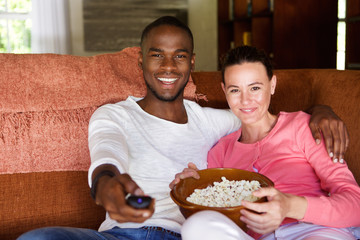 Mixed race couple watching a movie at home