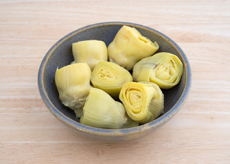 Artichoke hearts in a bowl on a wood table top