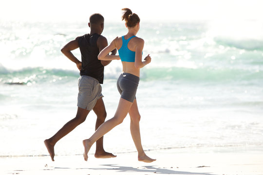 Young couple running along the beach - Powered by Adobe