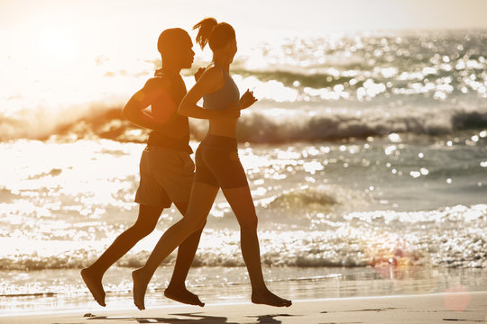 Couple running along the beach at sunset