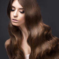 Naklejka premium Beautiful brunette girl with a perfectly curls hair and classic make-up. Beauty face. 