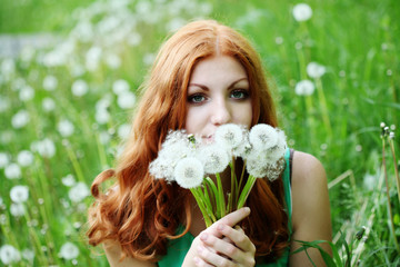 Lifestyle portrait of young spring fashion woman blowing dandelion in spring garden.    