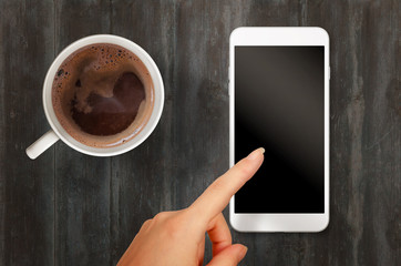 Fototapeta na wymiar Woman touch smart phone with isolated white screen for mockup. Top view scene with coffee.