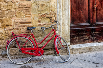 Fototapeta na wymiar Red bicycle leaning against a wall in Pienza