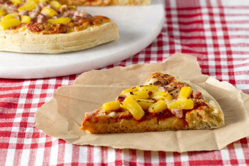 slice of hawaiian pizza on piece of paper