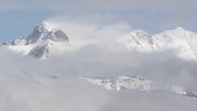 Snow covered Arche, Aiguille, Petite Aiguille and Piolit peaks with fast moving clouds, early winter morning. Ecrins National Park, Southern French Alps