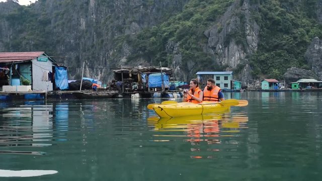 Couple of tourists travel in floating village, Halong Bay, Vietnam. 