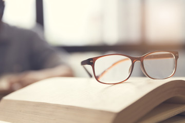 eyeglasses with woman reading book in room