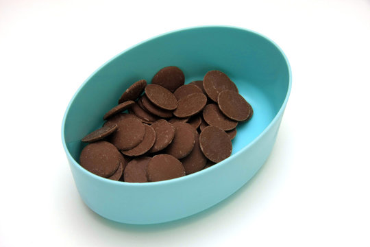 Milk Chocolate Buttons In A Blue Container On A White Background