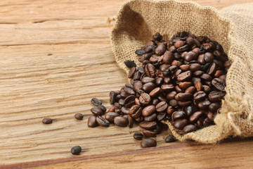 Coffee beans with burlap sack on wood background