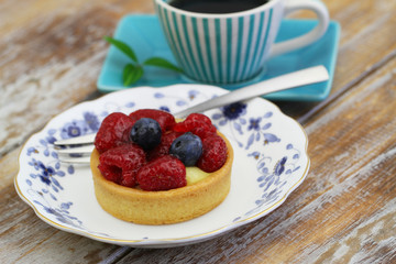 Cream cake with custard and fresh strawberries and blueberries on vintage plate
