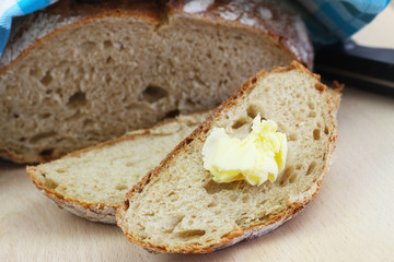 Slices of traditional rustic rye bread with butter on wooden board, closeup
