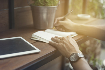 man writing on notebook with digital tablet