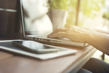 man's hand typing on laptop computer with smartphone and digital