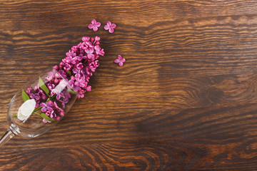 Obraz na płótnie Canvas Wineglass with violet lilacs
