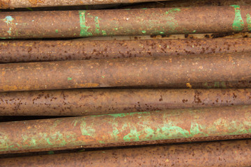 A pile of brown rusty iron pipes with spots of paint